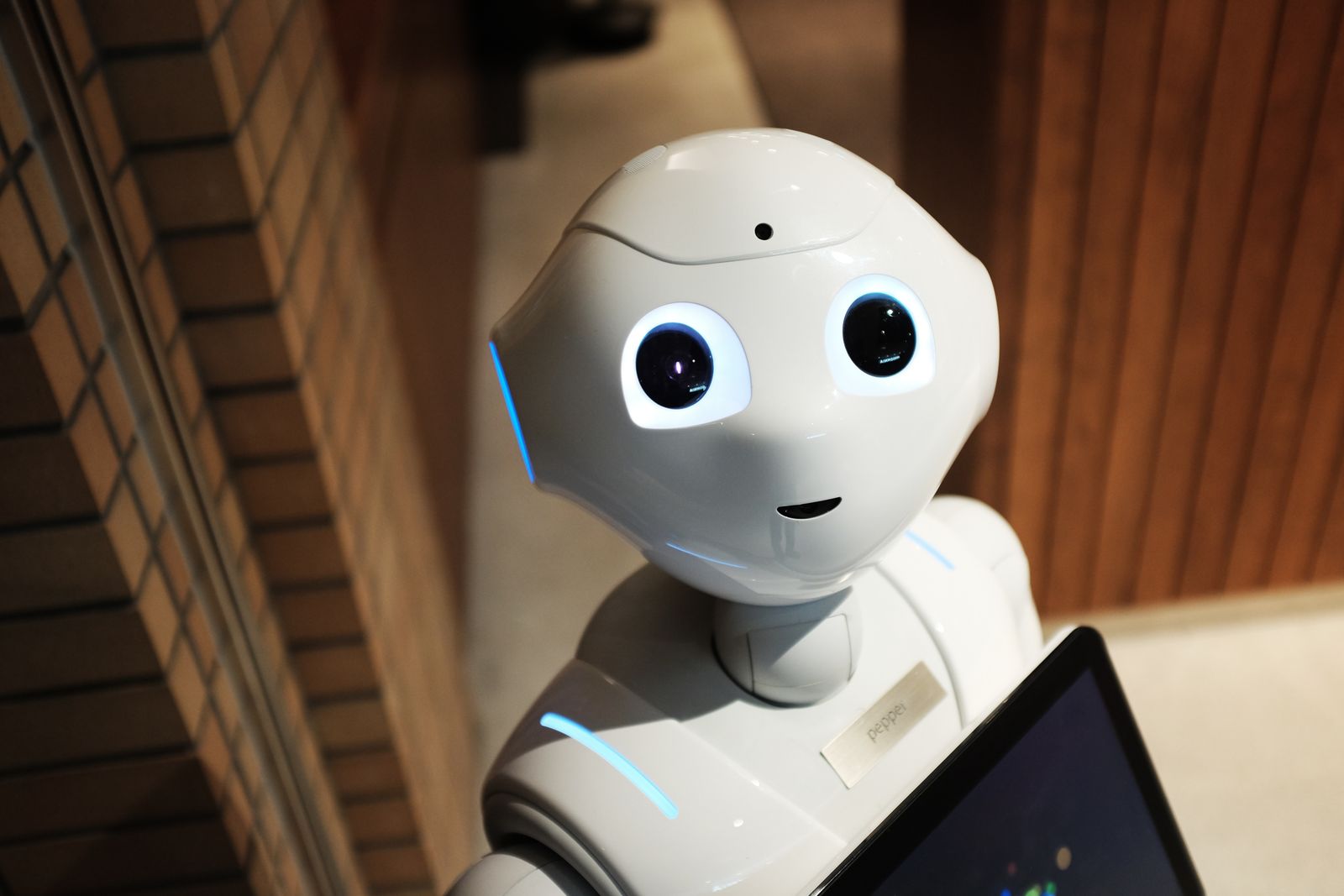 Robot humanoïde blanc tenant une tablette, symbole de l'intelligence artificielle