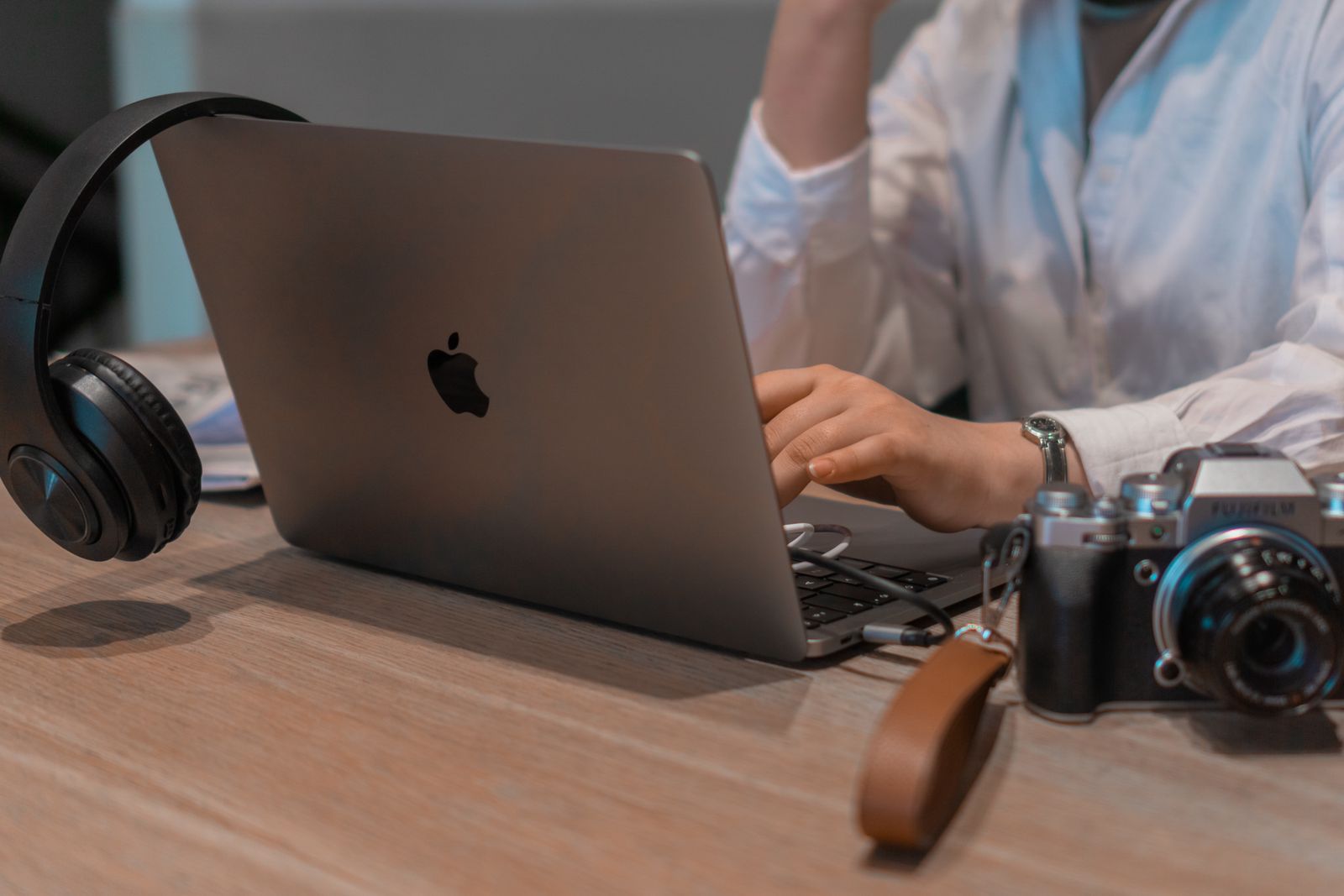 Close-up of a person working remotely with a laptop, headphones, and camera. Ideal for tech and lifestyle themes.